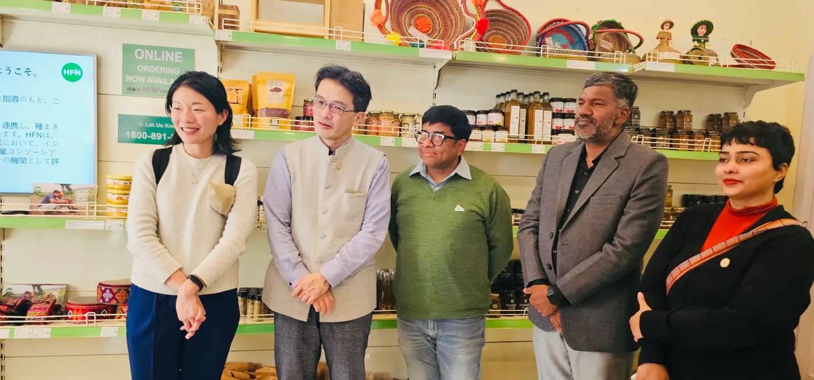 JICA and HFN representatives standing inside HFN Store with producer products on the shelves.